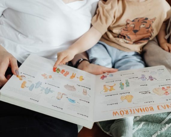 A mother and her son enjoy reading a children's book together while sitting on a cozy couch.